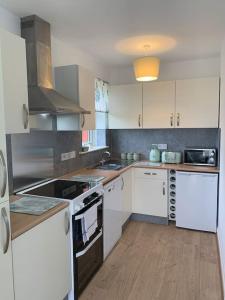 a kitchen with white appliances and a wooden floor at Modern, Stylish lodge with Paddock Views in Sandwich