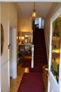 a hallway with a staircase with a chandelier at Knightsrest in Burnham on Sea