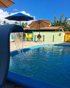 a water fountain in a pool with umbrellas at Pousada Canto dos Artistas in Porto De Galinhas