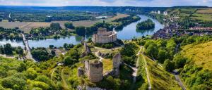 an old castle on a hill next to a river at La Parenthèse Andelysienne in Les Andelys