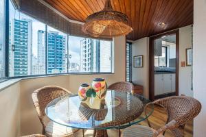 comedor con mesa de cristal y sillas de mimbre en GDGT121-Conforto com 3Q+3WC+2vagas e churrasqueira, en Balneário Camboriú