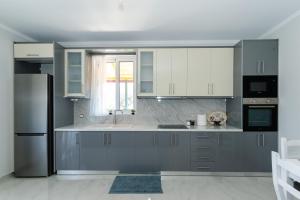 a kitchen with white cabinets and a stainless steel refrigerator at Santa Saranda Villas in Pllakë