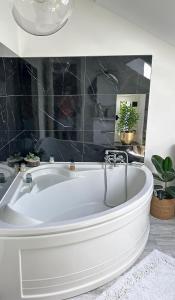 a white bath tub in a bathroom with black tiles at Maison familiale en Périgord Dordogne in Saint-Astier +15 photos