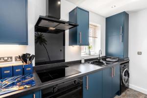 a kitchen with blue cabinets and a black counter top at Doncaster Lakeside Paradise Place in Doncaster
