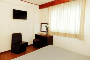 a bedroom with a bed and a chair and a window at Hotel Rex in Toluca