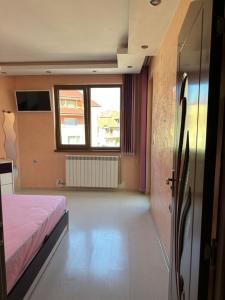 a bedroom with a bed and a large window at Луксозен апартамент in Vratsa