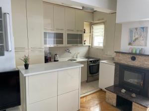 a kitchen with white cabinets and a fireplace at Heart of Prishtina Apartment in Pristina