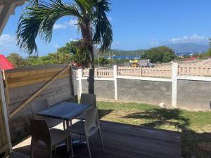 a table and chairs on a deck with a palm tree at Petit bungalow Chez Angelo in Terre-de-Haut