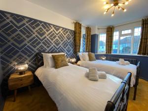 a bedroom with two beds and a blue wall at Eclectic Bungalow Parking Nr Beach in Kent