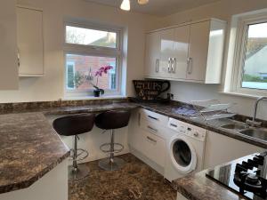 a kitchen with white cabinets and a washer and dryer at Eclectic Bungalow Parking Nr Beach in Kent