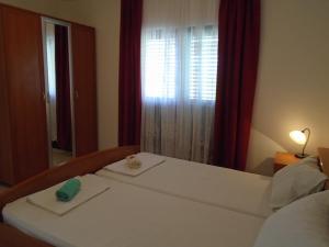 una camera con letto bianco, finestra e specchio di Apartments Sveti Anton a Orebić (Sabbioncello)