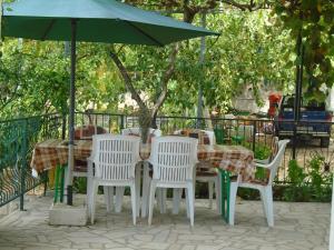 un tavolo e sedie sotto un ombrellone verde di Apartments Sveti Anton a Orebić (Sabbioncello)