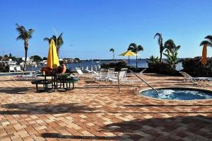 a person sitting under an umbrella next to a pool at Bayview Oceanside Condo with Pool and Private Balcony in St. Petersburg