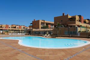 an empty swimming pool with buildings in the background at Casa Lara Fuerteventura in Corralejo
