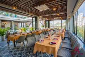 a row of tables and chairs in a room with windows at Roza Palace Cat Ba in Cat Ba