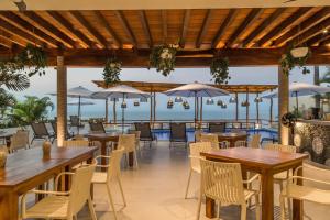 a restaurant with tables and chairs and a view of the ocean at Hotel Ysuri Bucerias in Bucerías
