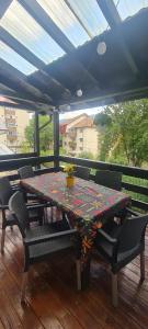 a table and chairs on a deck with a roof at Casa Ama in Buşteni