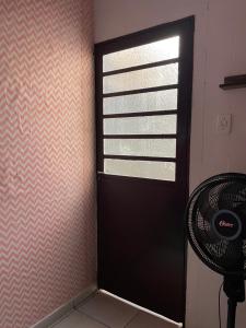 a black door in a room with a fan at Quarto rosa em frente moradia unicamp in Campinas