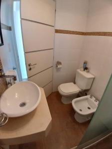 a bathroom with a white toilet and a sink at Departamento centrico in Tandil