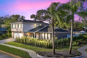 a house with a palm tree in front of it at Luxury Home, Heated Saltwater Pool, 5-Min to Beach in Seminole