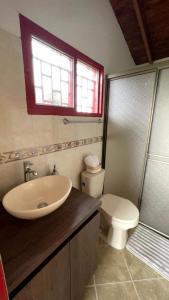 a bathroom with a sink and a toilet and a window at Cabaña Linda y acogedora in Guarne