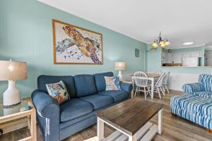 a living room with a blue couch and a table at Chateau By the Sea Oceanfront Unit H2 in Myrtle Beach