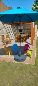a group of colorful chairs under a blue umbrella at Casa de Silvares - Piso Superior in Celorico de Basto
