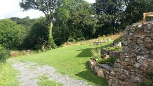un mur de pierre à côté d'un champ d'herbe dans l'établissement Farthings Hook Mill Holiday Cottage, à Henrys Moat