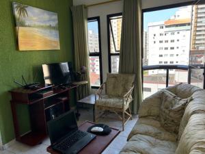- un salon avec un ordinateur portable sur un canapé dans l'établissement Lindo Apto 502 em PG Ocian, à Praia Grande