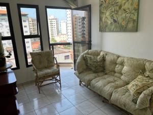 un salon avec un canapé et une chaise dans l'établissement Lindo Apto 502 em PG Ocian, à Praia Grande