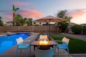 a patio with a table and chairs and an umbrella at Putt Putt Hot Tub Game Room Pool Cornhole in Chandler +46 photos