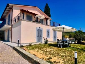 a house with a table and an umbrella in the yard at Bellavista La Querce in Foiano della Chiana