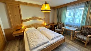 sypialnia z łóżkiem i krzesłem w obiekcie Hotel Alpenrose w mieście Zöblen