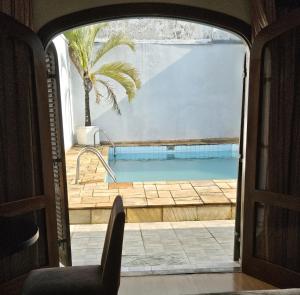 a door leading to a swimming pool with a palm tree at Charmosa e ampla suíte in Sao Paulo