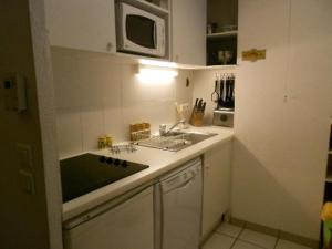 une petite cuisine avec un évier et un micro-ondes dans l'établissement Résidence Pic De Lia - Appartement 6 personnes au centre du village MAE-6164, à Cadeilhan-Trachère