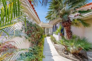 a house with a palm tree next to a building at Southern Hills Charm Permit# 65256 in La Quinta