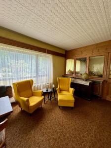 ein Wohnzimmer mit 2 gelben Stühlen und einem Tisch in der Unterkunft Strandhotel Prinz in Ossiach