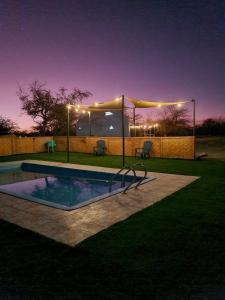 a swimming pool at night with a tent and lights at Domo en el desierto in La Huaica
