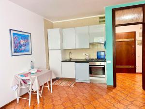 cocina con armarios blancos, mesa, mesa y sillas en AURORA GARGEN IN CENTRO, en Trieste