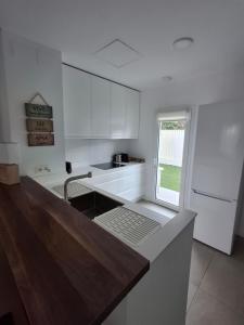 a kitchen with white cabinets and a sink and a window at Green Simon, piso nuevo con piscina 2024 in San Juan de Aznalfarache