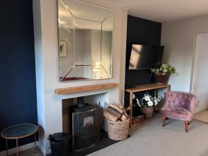 a living room with a fireplace and a mirror at King Arthur's Rest House, Hot Tub & Garden Sleeps 10 in South Cadbury