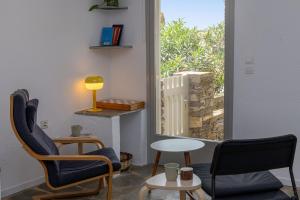 a room with two chairs and a table and a window at By The Stone Tinos in Triandáros