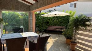 a patio with a table and an umbrella and a bench at Apartment Malija Cikloped in Izola