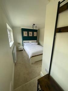 a bedroom with a white bed and a mirror at Rondor Cottage in Bridgnorth +3 photos