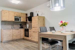 a kitchen with wooden cabinets and a table with chairs at Apartment Swim and Relax in Moravske-Toplice