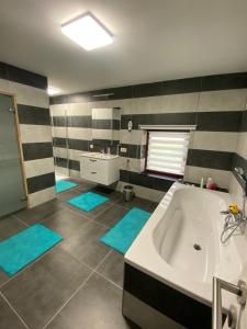a bathroom with a tub and a sink and blue mats at gite du Berdinsart in Haut-le-Wastia +5 photos