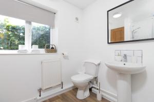 a white bathroom with a toilet and a sink at 2BR retreat with Driveway in Warwick +32 photos