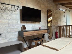 a bedroom with a desk with a tv on a stone wall at Techo de piedra in Kastellákia