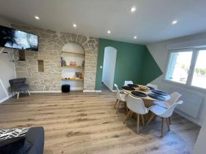 a dining room with a table and chairs and a stone wall at Les 3G in Abbeville