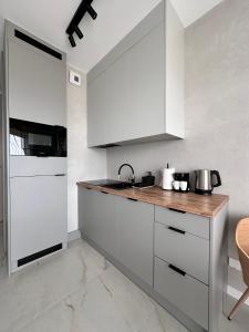 a kitchen with white cabinets and a wooden counter top at Vidok Residence Apartments in Młoszowa
